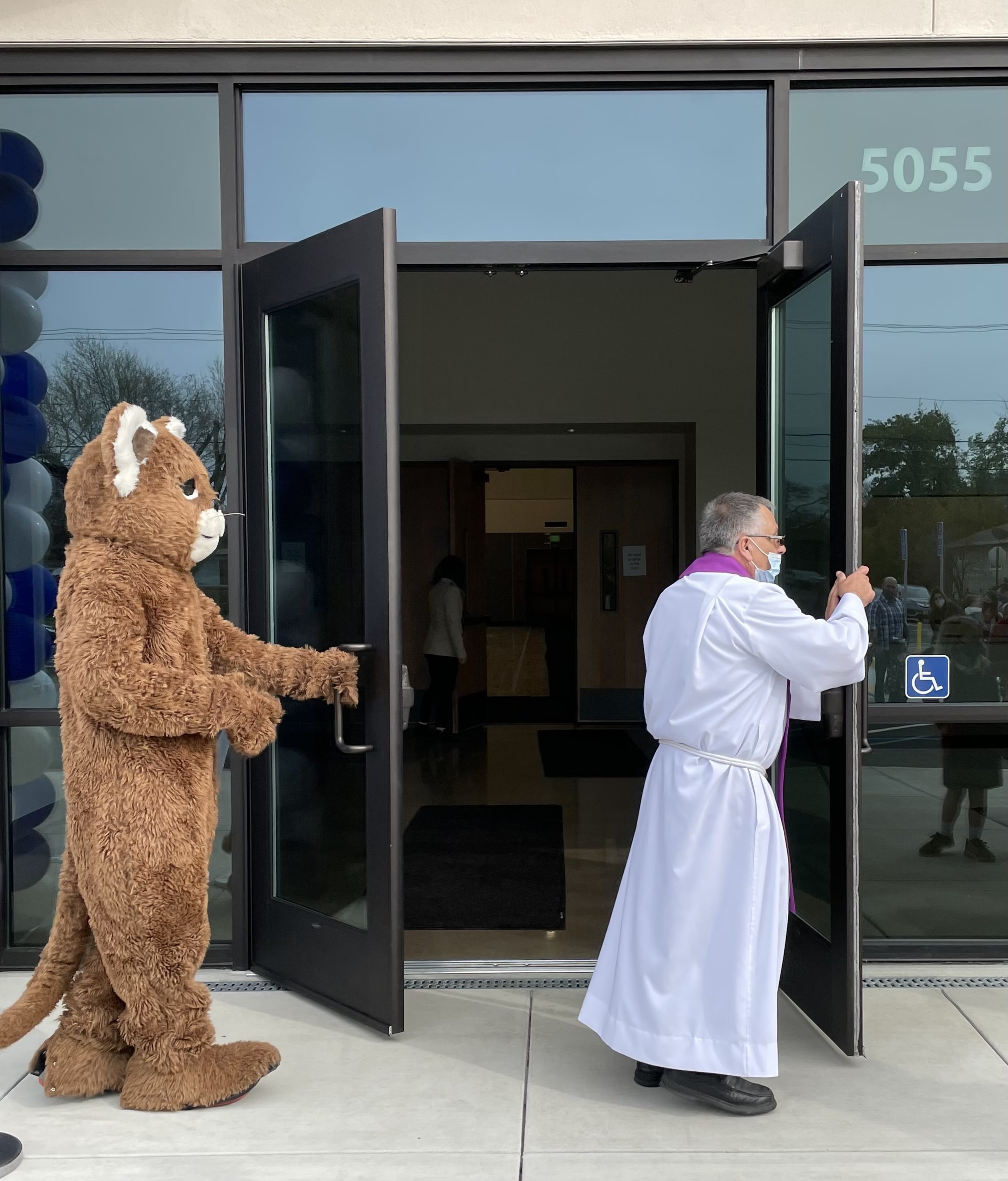 Fr. Eduino and the OLA Cougar mascot open the doors to Affinito Hall.